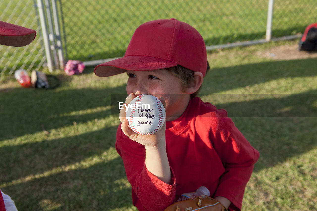 Young boy holding his player of the game baseball on the tball field