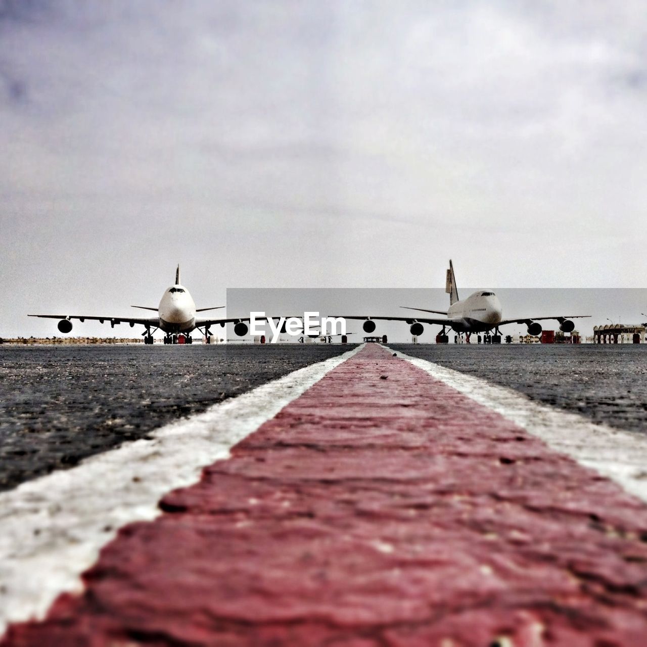 Surface level of airport runway and airplanes against cloudy sky