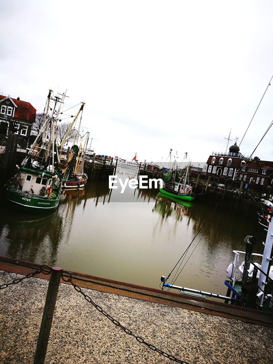 BOATS MOORED ON HARBOR AGAINST SKY