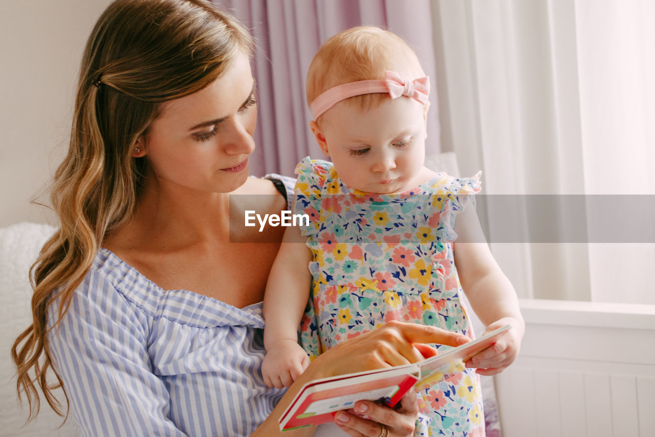 Mother reading book to daughter at home