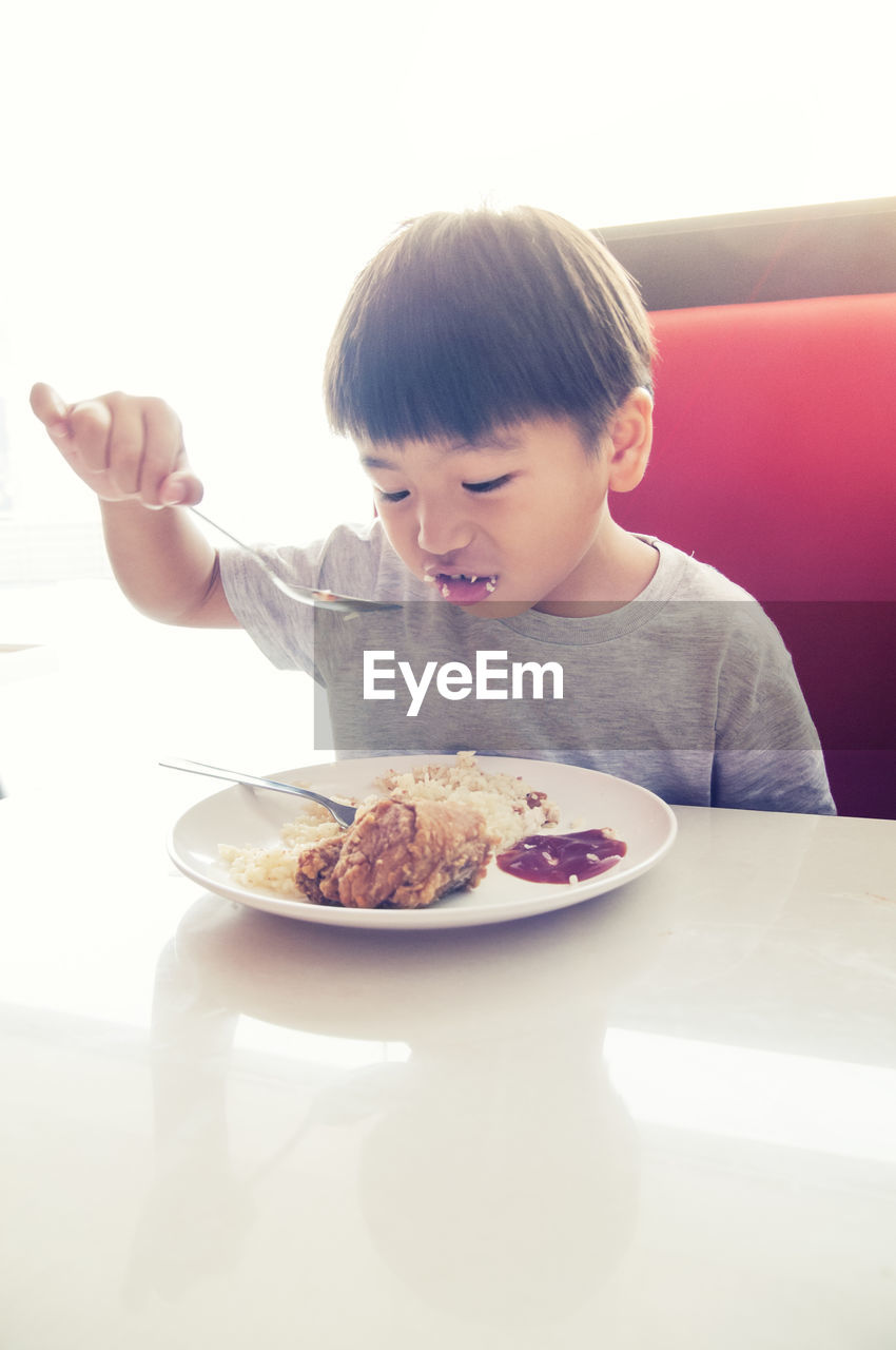 Close-up of boy having food at table