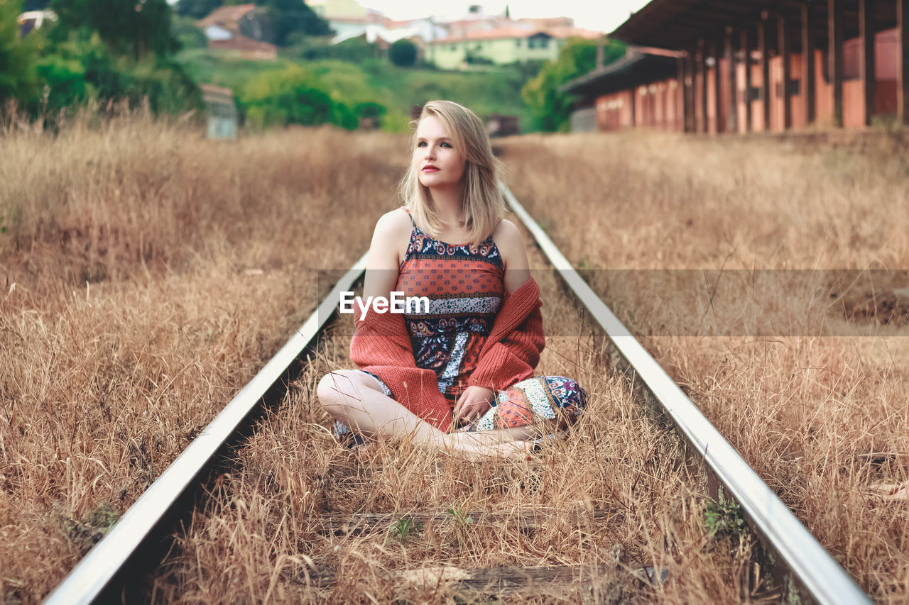 Woman sitting on railroad track