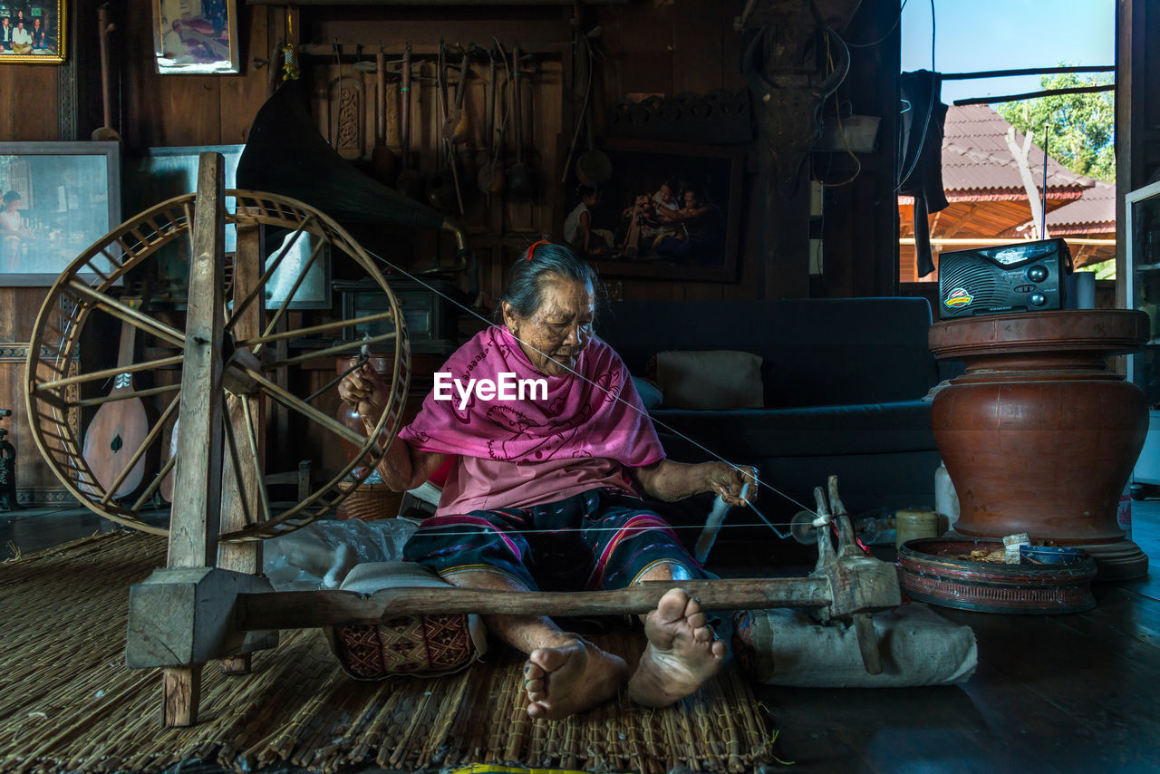 FULL LENGTH OF WOMAN SITTING ON WOOD