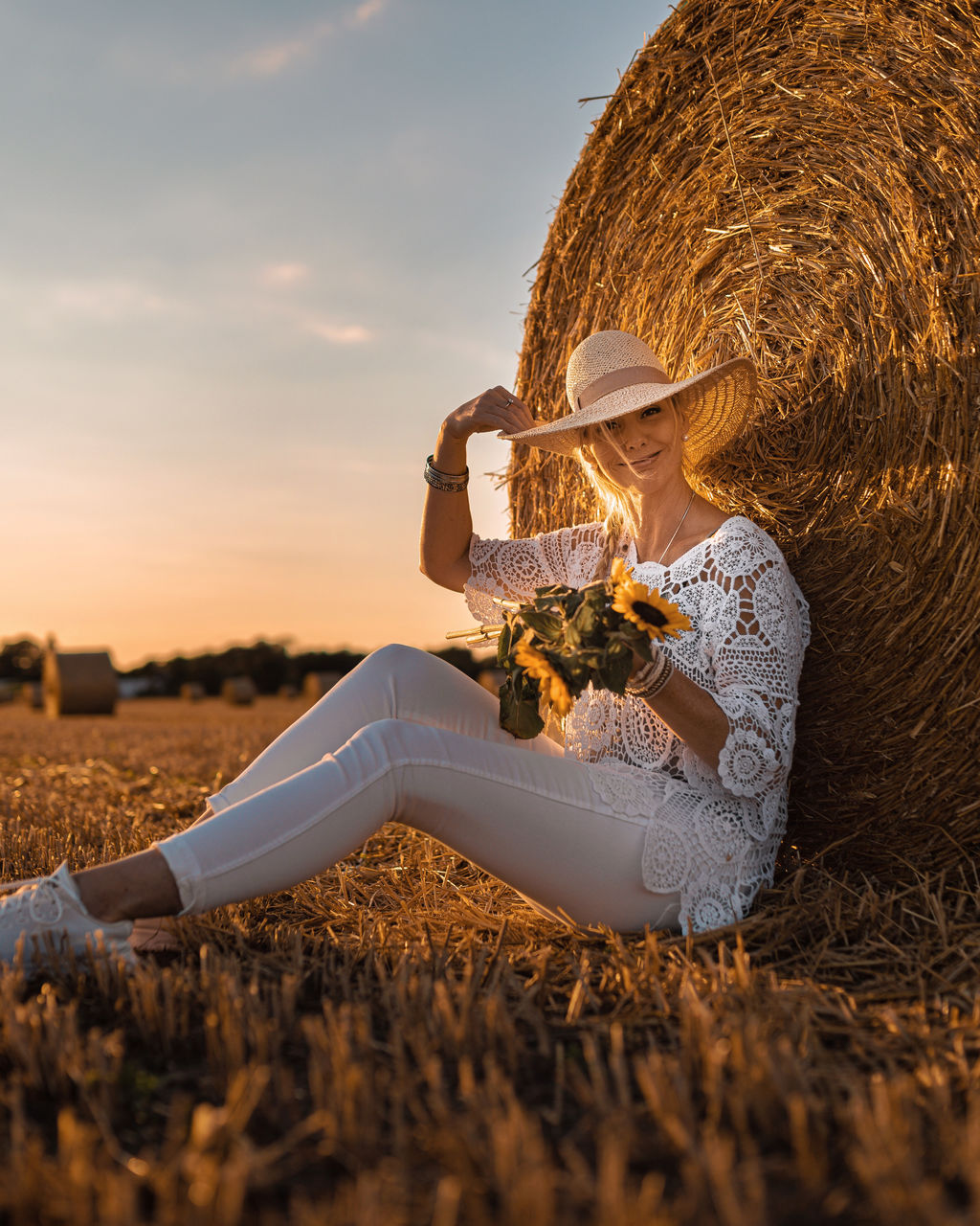 Woman sitting on field against sky