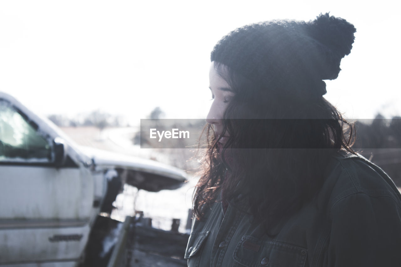 Close-up of woman wearing knit hat while standing against clear sky