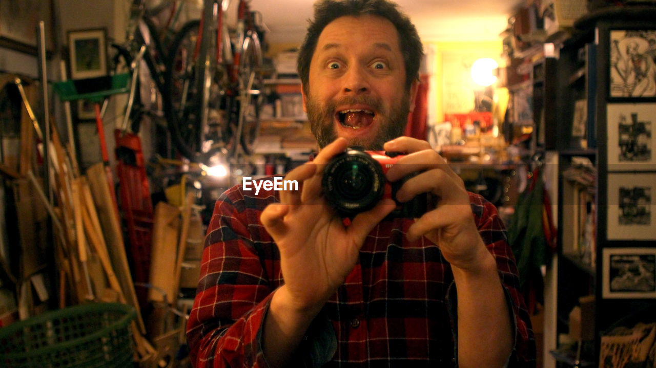 Portrait of surprised man photographing with digital camera in store