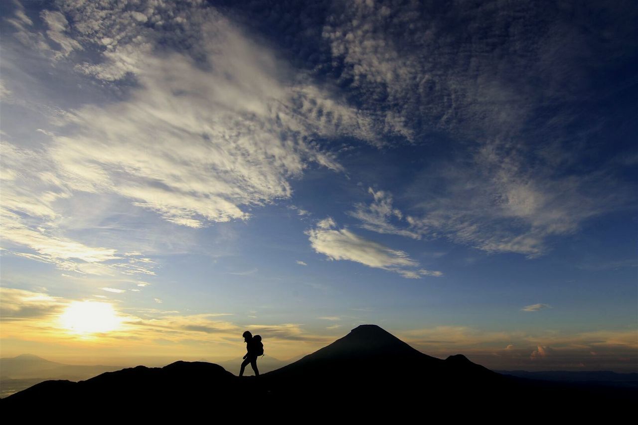 Silhouette person on mountain against sky during sunrise