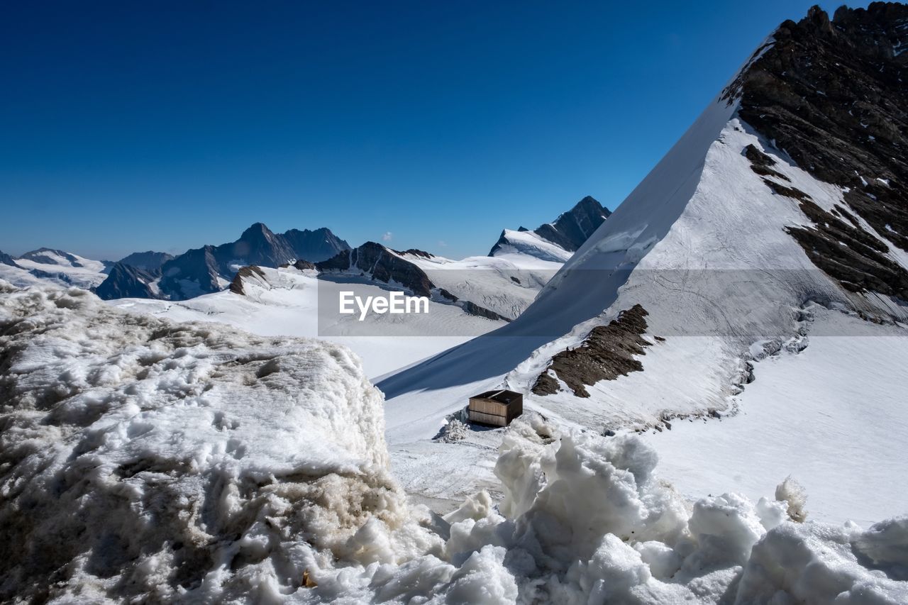 Scenic view of snowcapped mountains against clear blue sky