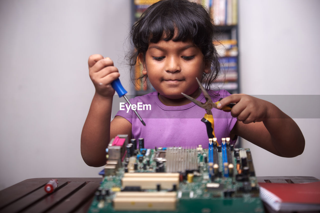 Little girl playing with motherboard computer at home