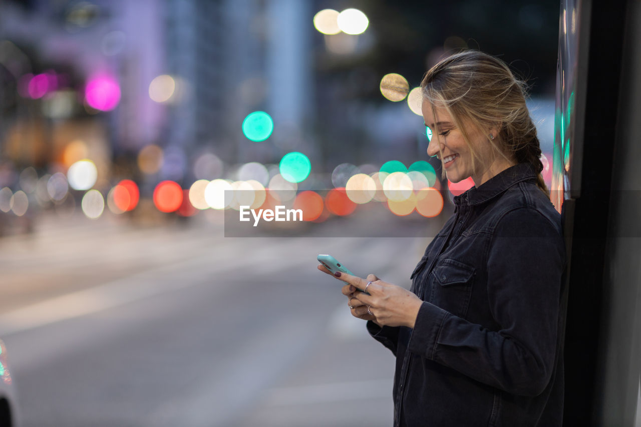 Woman with smartphone at night time on the street. mobile phone, technology, urban