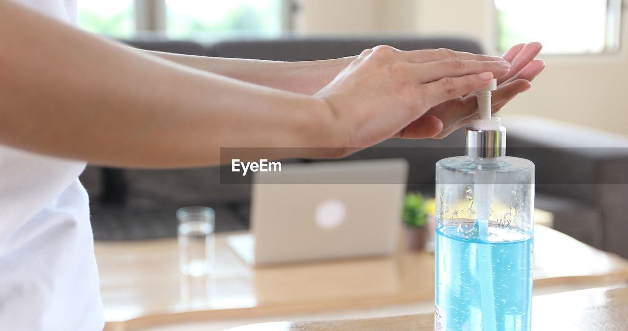 CLOSE-UP OF HAND HOLDING GLASS BOTTLE