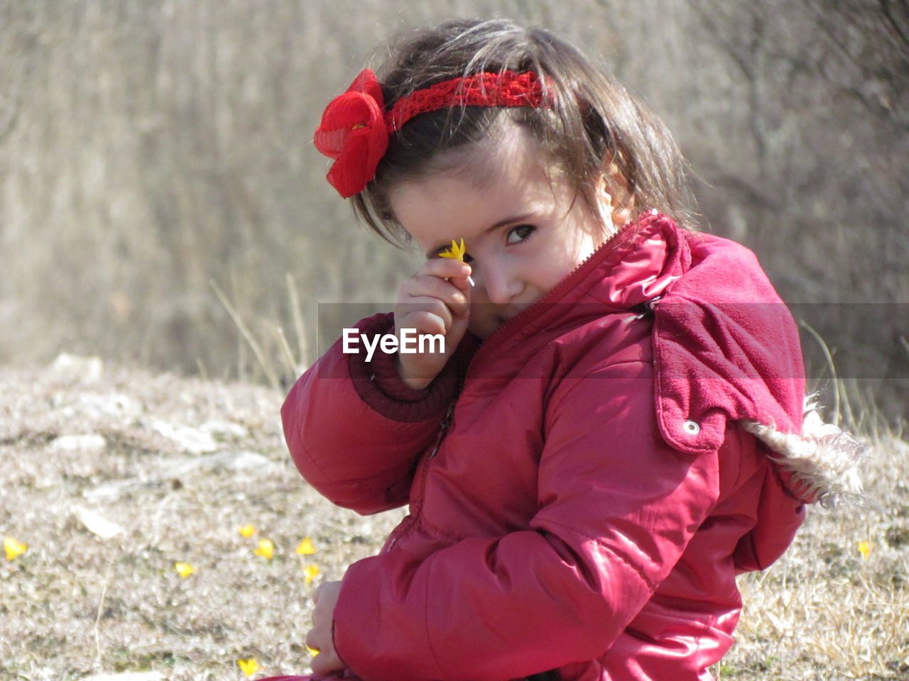 Portrait of girl showing flower on field