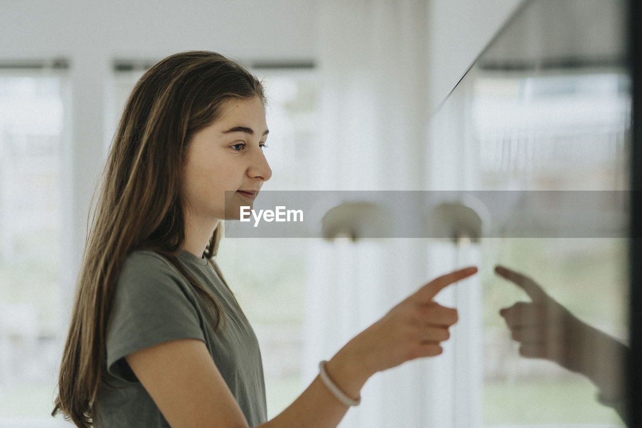 Side view of girl using smart tv while standing at home