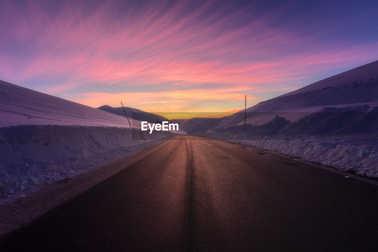 Empty road against sky during sunset