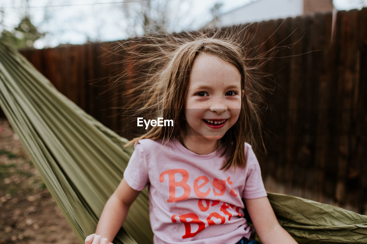 Young girl with static hair sitting on hammock