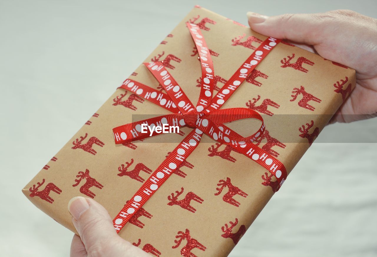 Cropped hands holding gift box against gray background