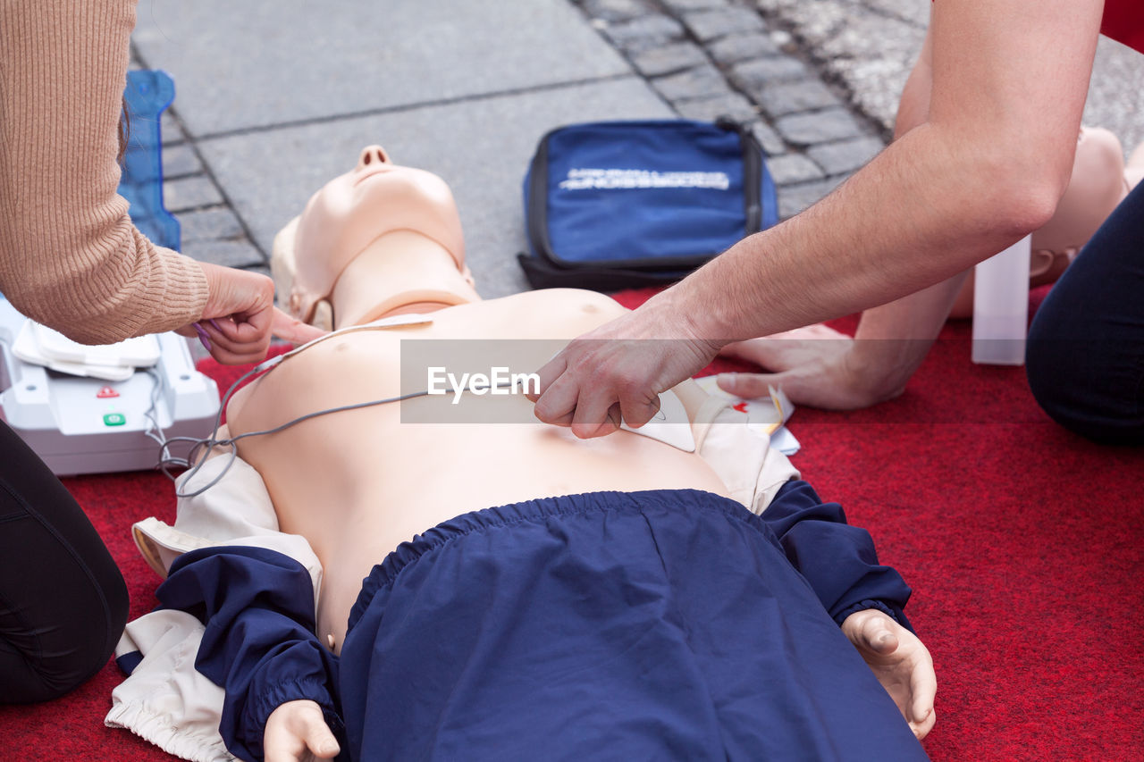 Midsection of instructor teaching paramedic while performing cpr on dummy