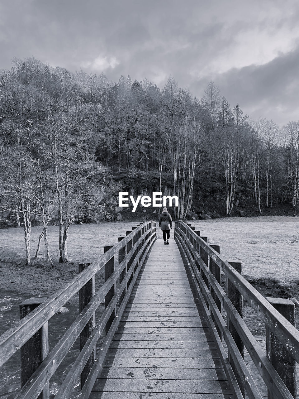 Black and white woman walking across a wooden bridge