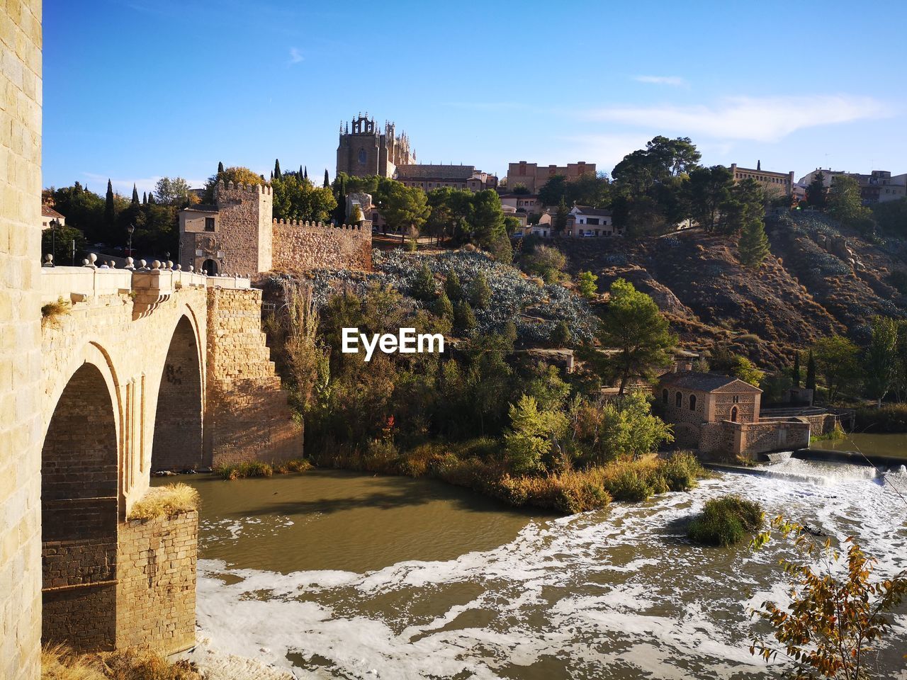 Arch bridge over river against buildings