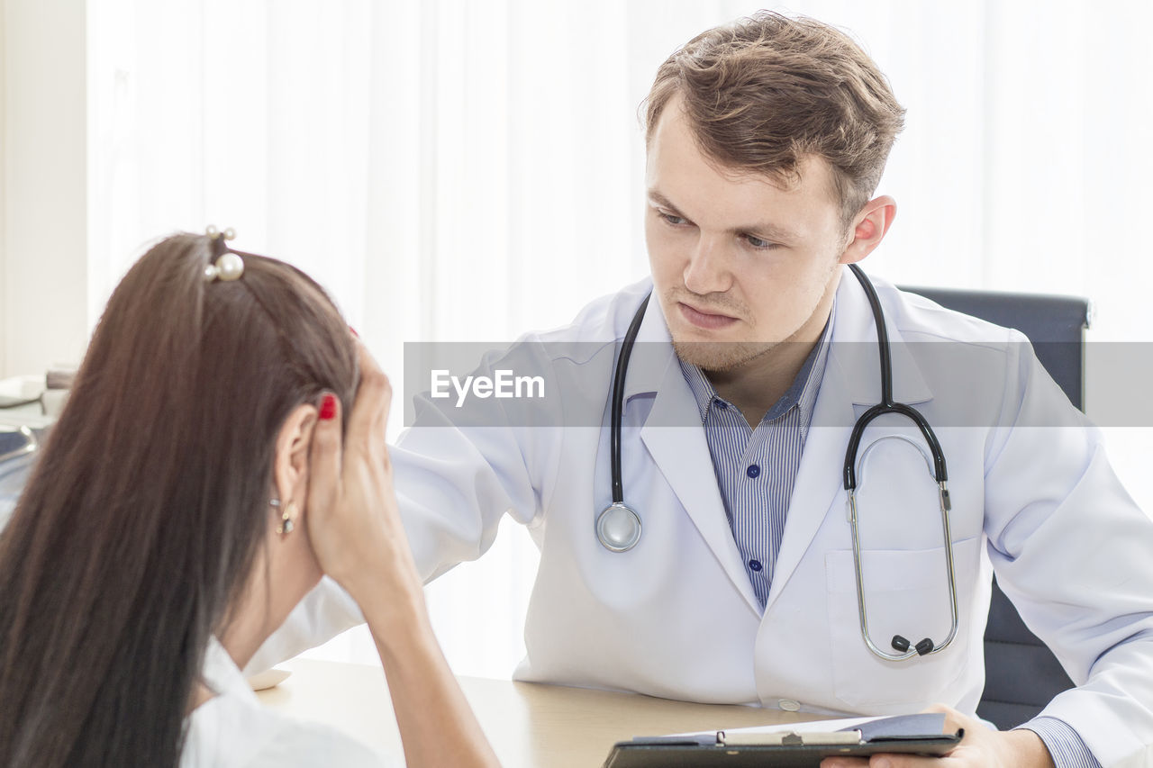 Doctor looking at woman sitting in hospital