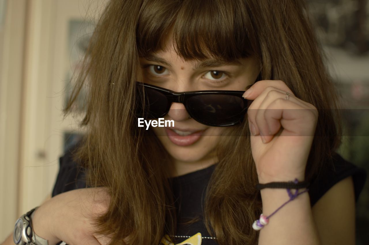 Close-up portrait of smiling young woman wearing sunglasses