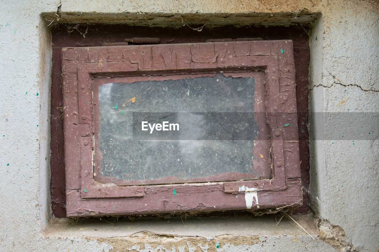 CLOSE-UP OF WEATHERED WINDOW ON WALL