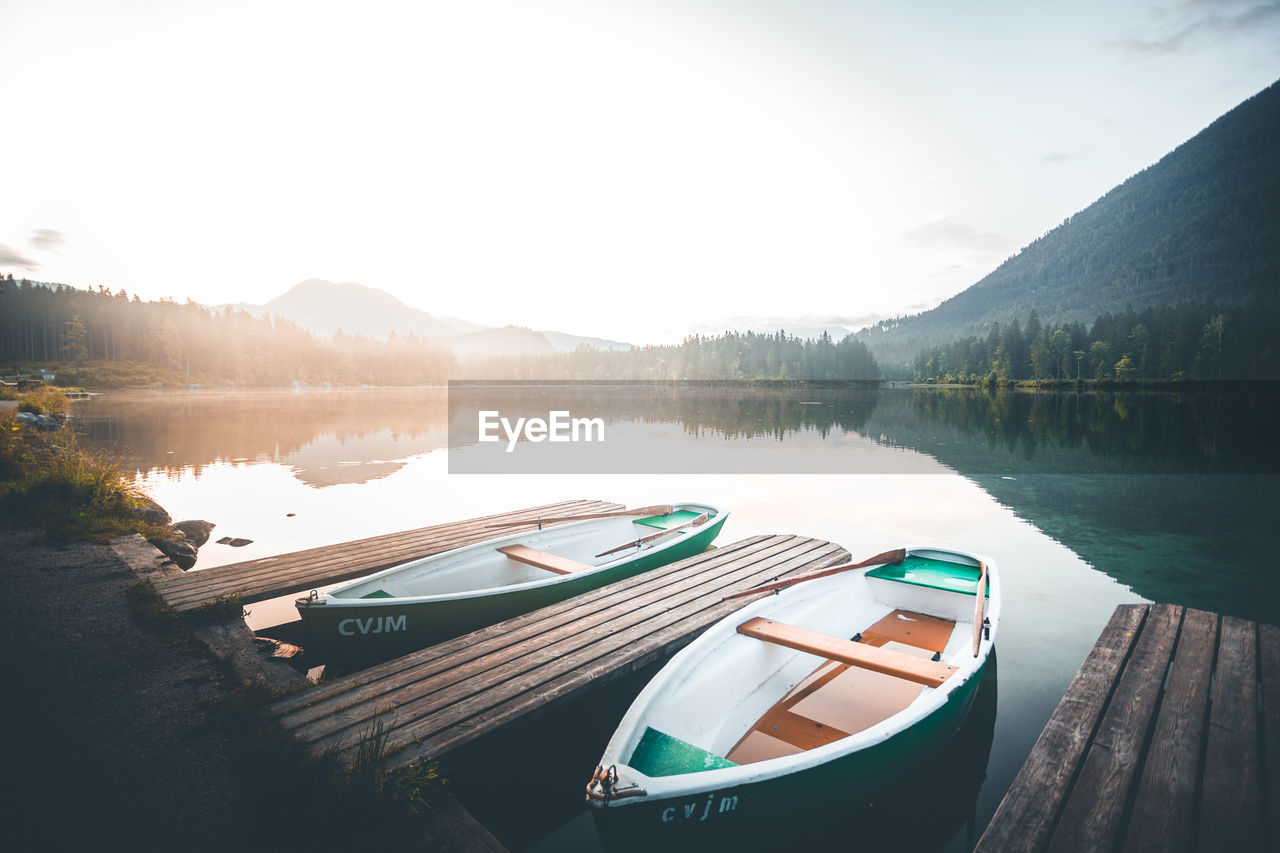 Boats moored at scenic lake against sky