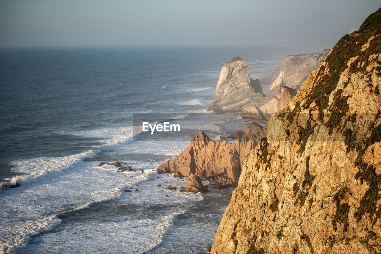 Scenic view of sea and rocky coast against sky