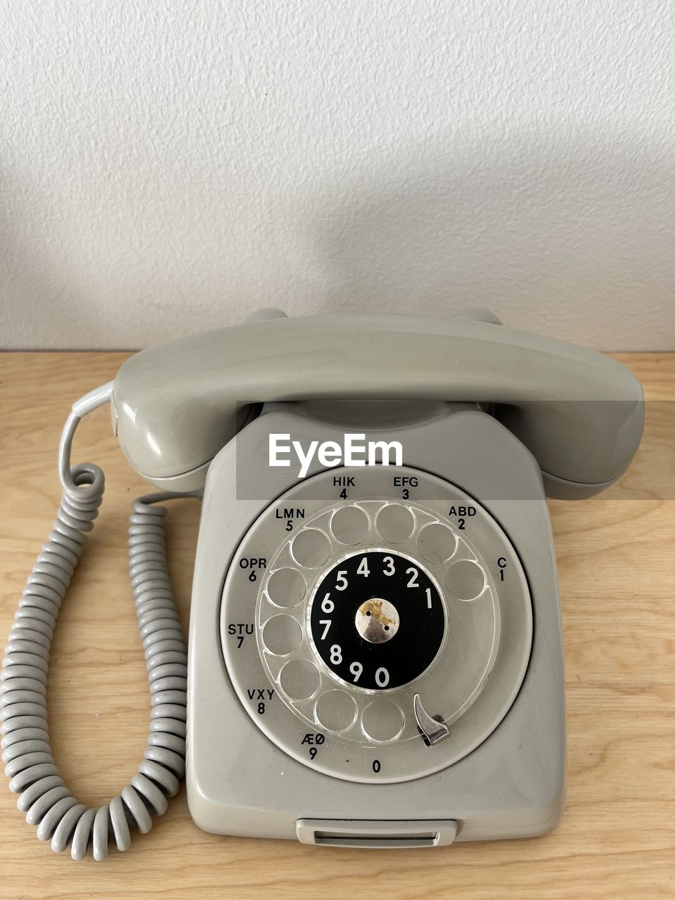 technology, corded phone, indoors, telephone, retro styled, table, landline phone, communication, no people, wood, telephone receiver, number, wall - building feature, rotary phone, cable, nostalgia, equipment