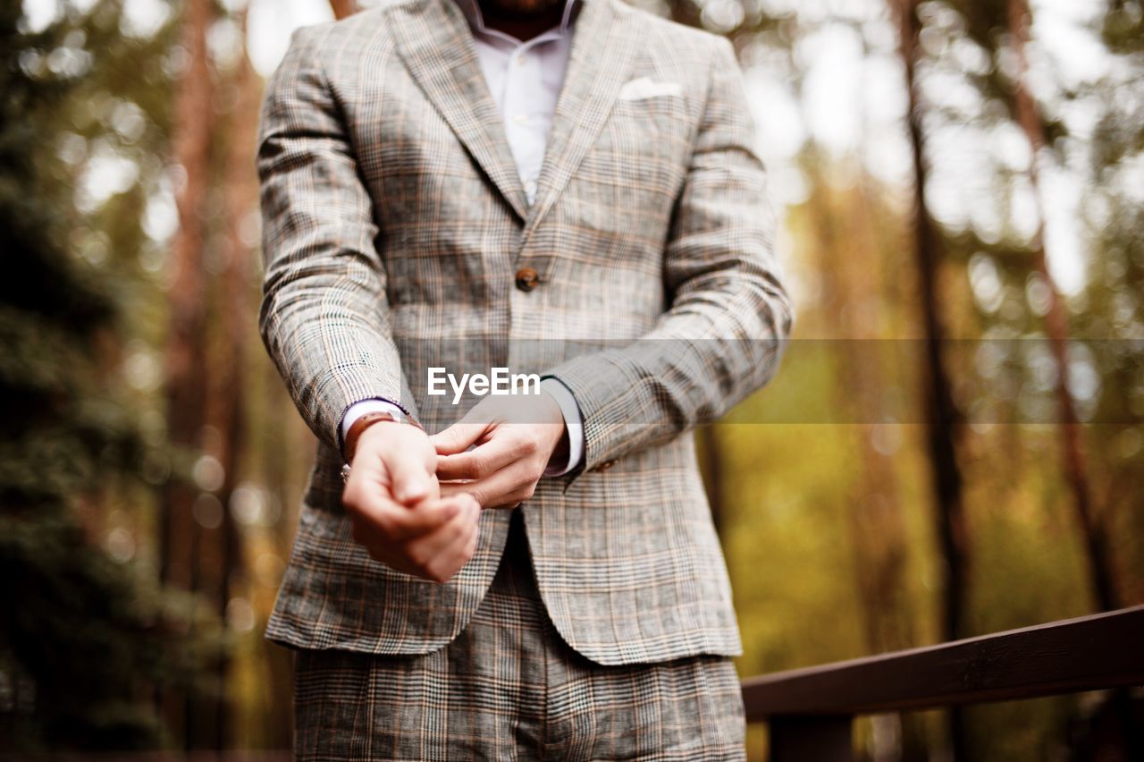 Midsection of well-dressed man standing in park