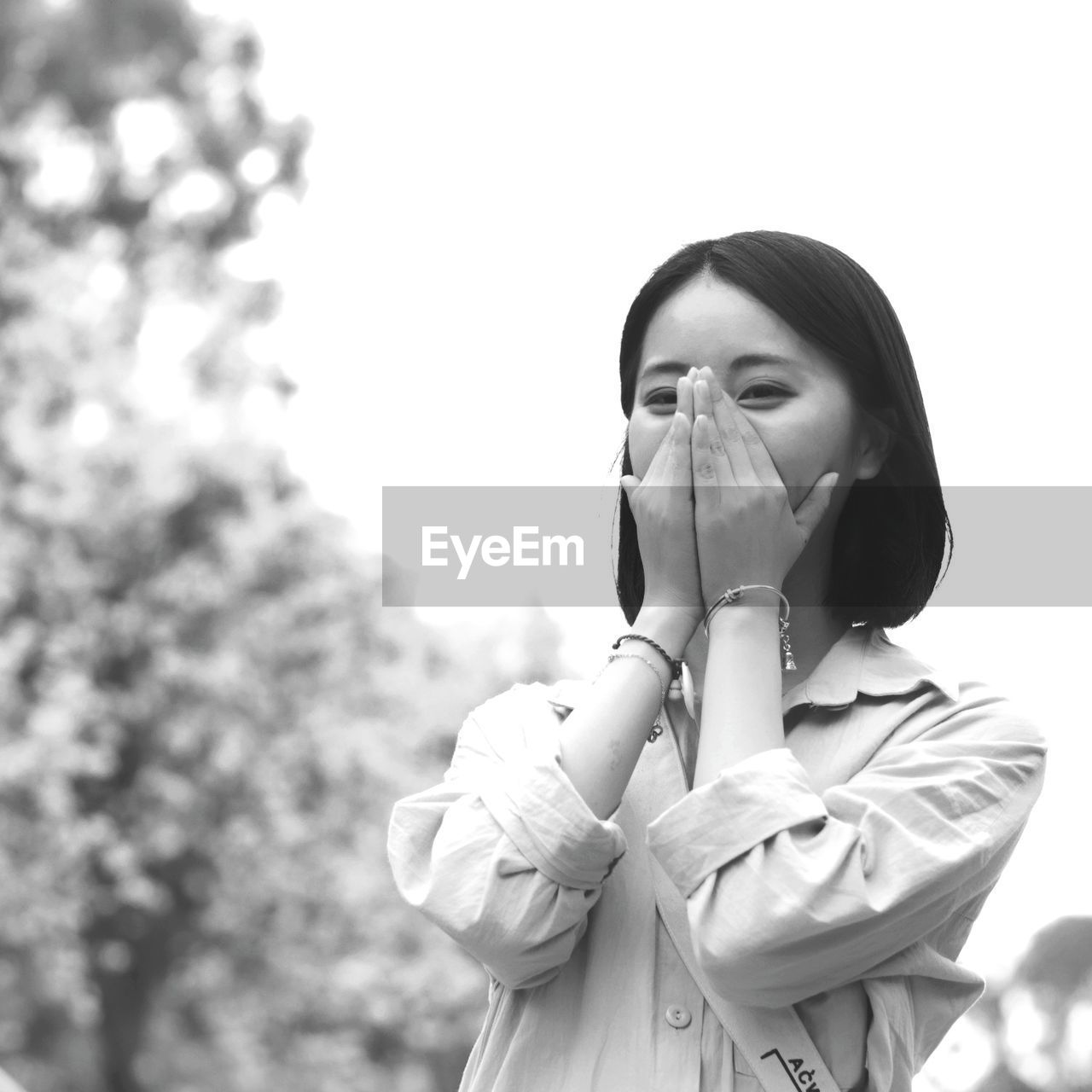 Woman covering mouth against clear sky