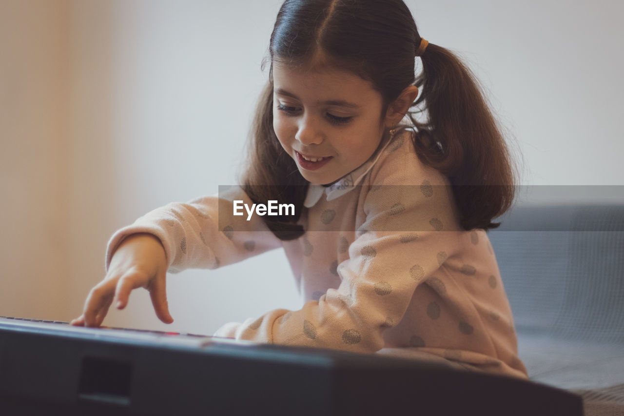 A little girl plays the electric piano.