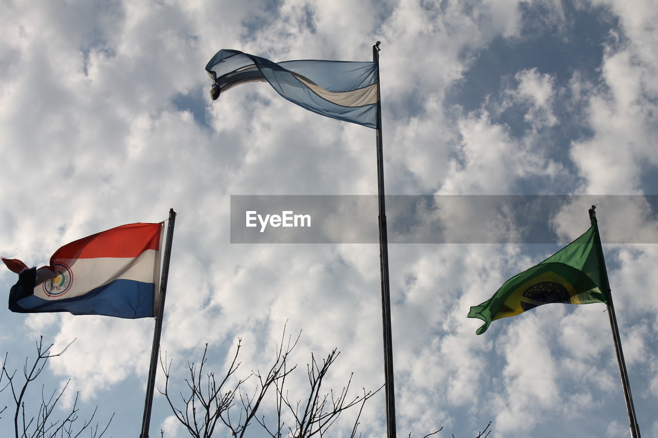 Low angle view of flags against cloudy sky