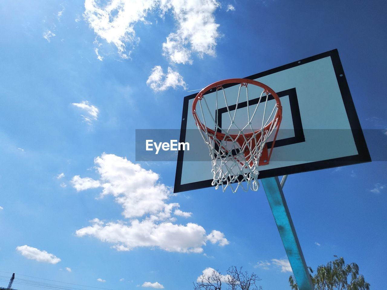 Low angle view of basketball hoop against blue sky during sunny day