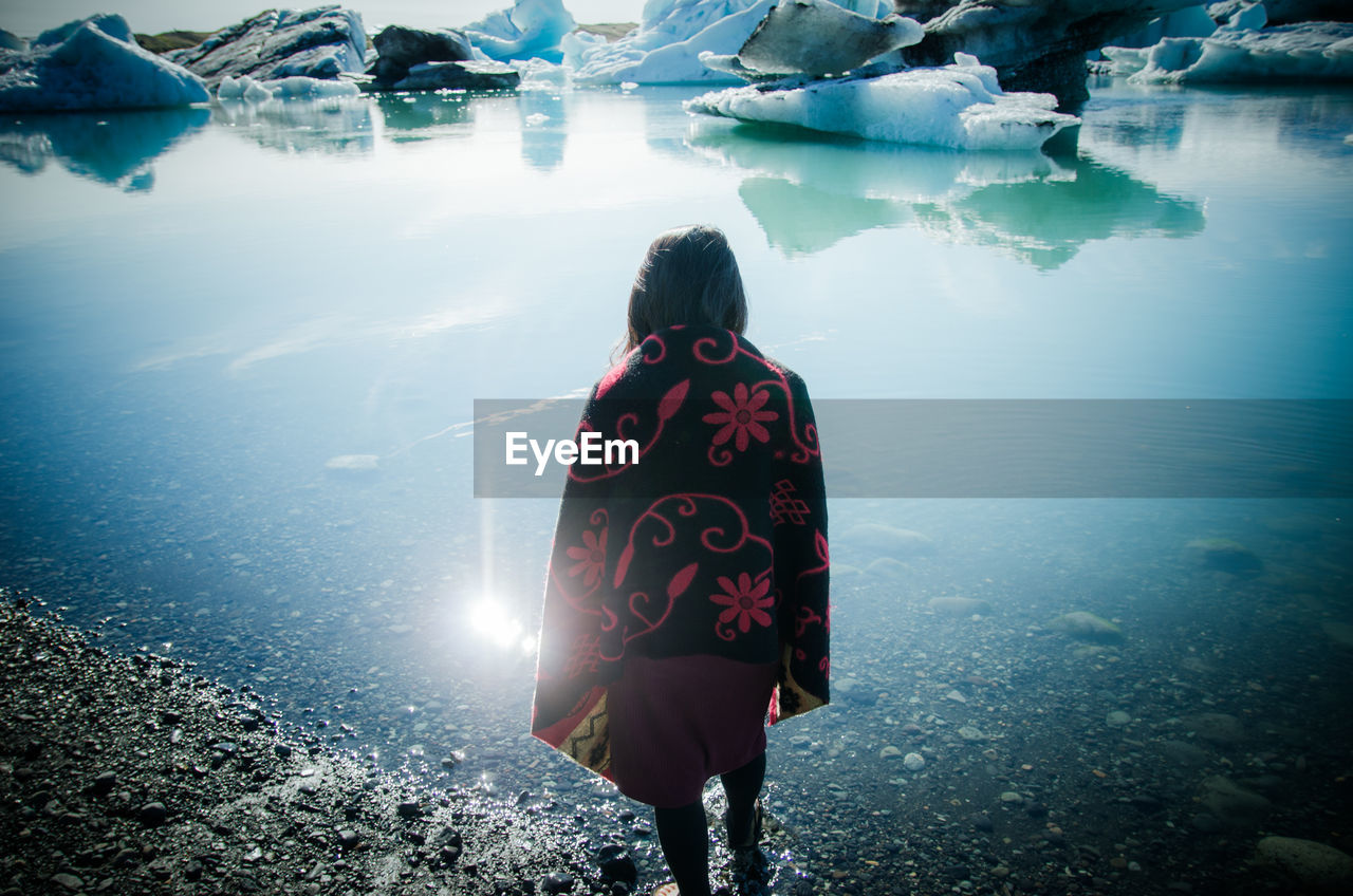 Rear view of woman standing by lake