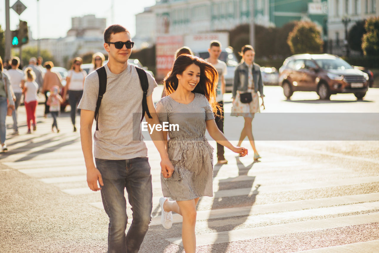 Smiling young couple walking on road in city