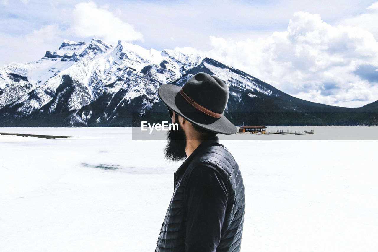 Rear view of man in fedora hat looking at view against cloudy sky