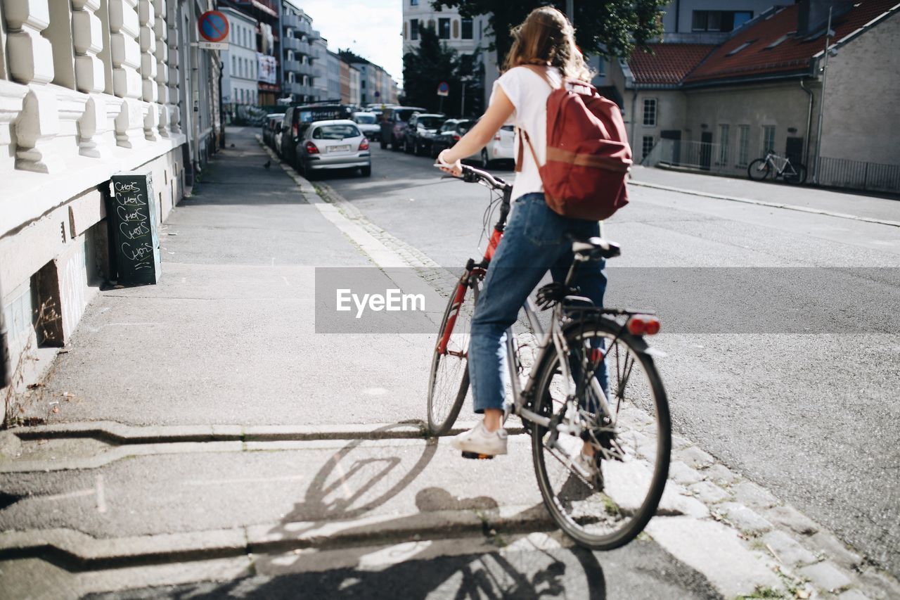 Young woman with bicycle on road in city