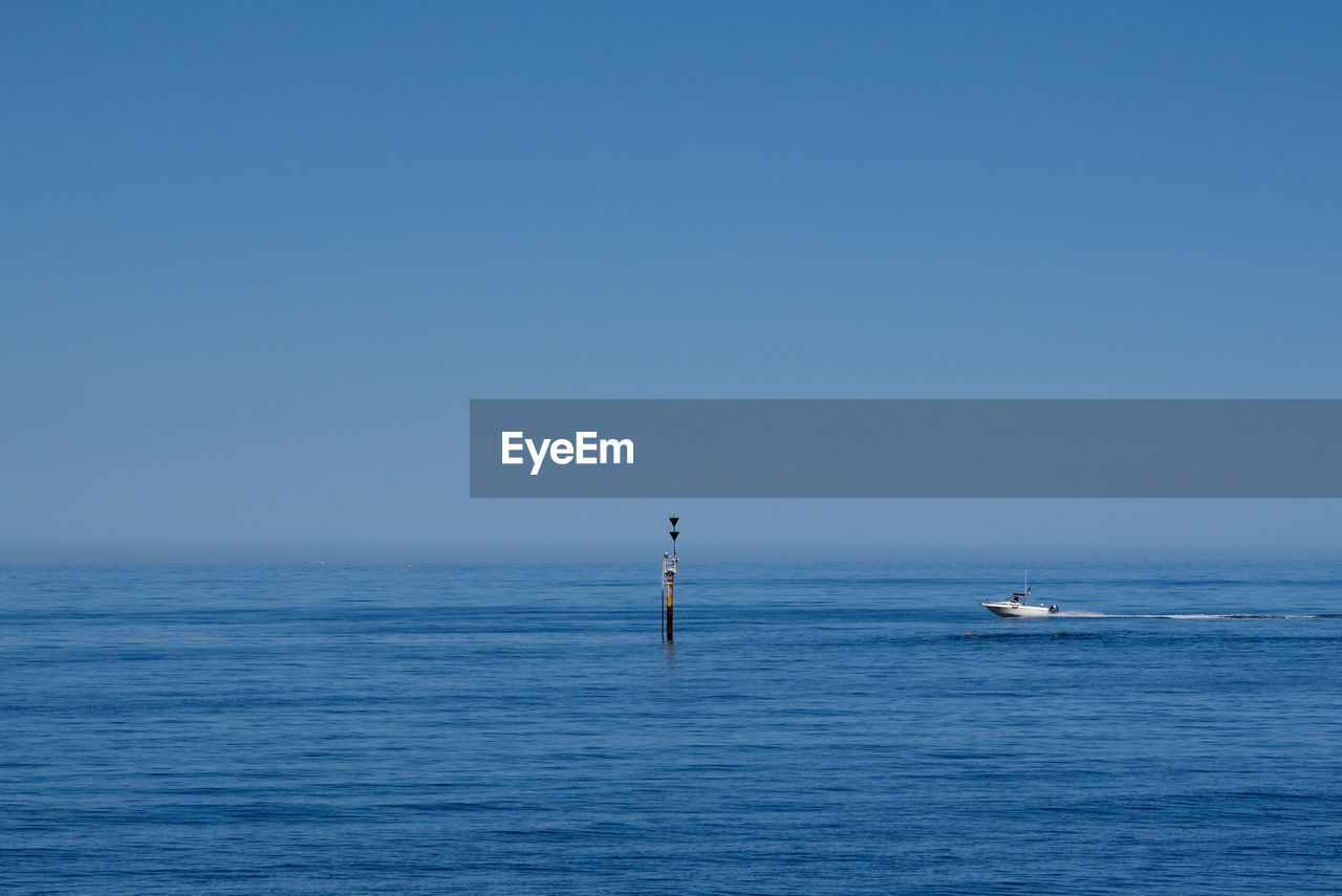 Sailboat in sea against clear blue sky