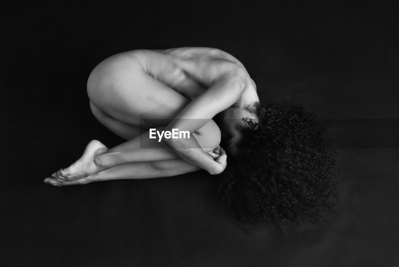 Portrait of naked woman over black background
