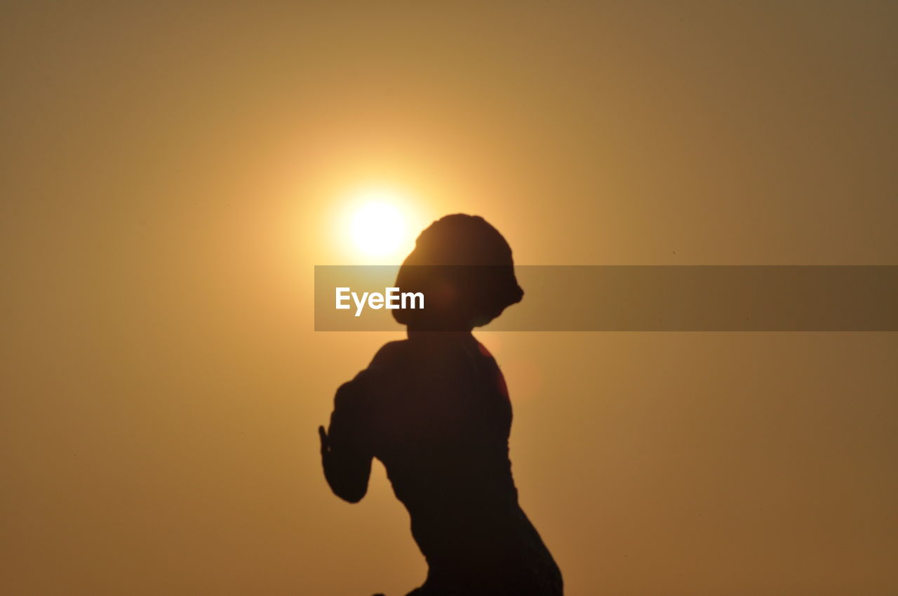 Silhouette man standing against orange sky