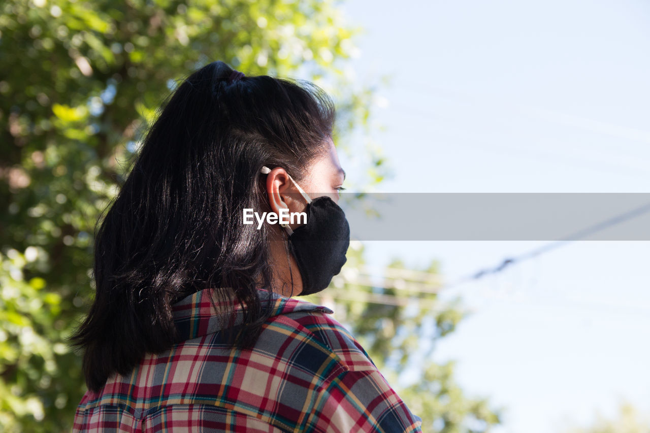 Back portrait of young woman wearing surgical face mask