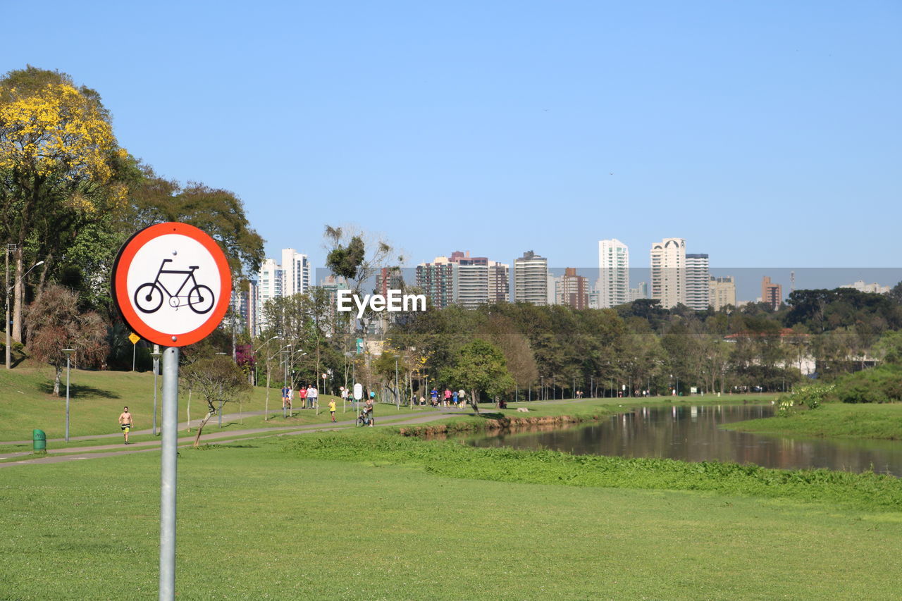 Road sign on field at park against sky