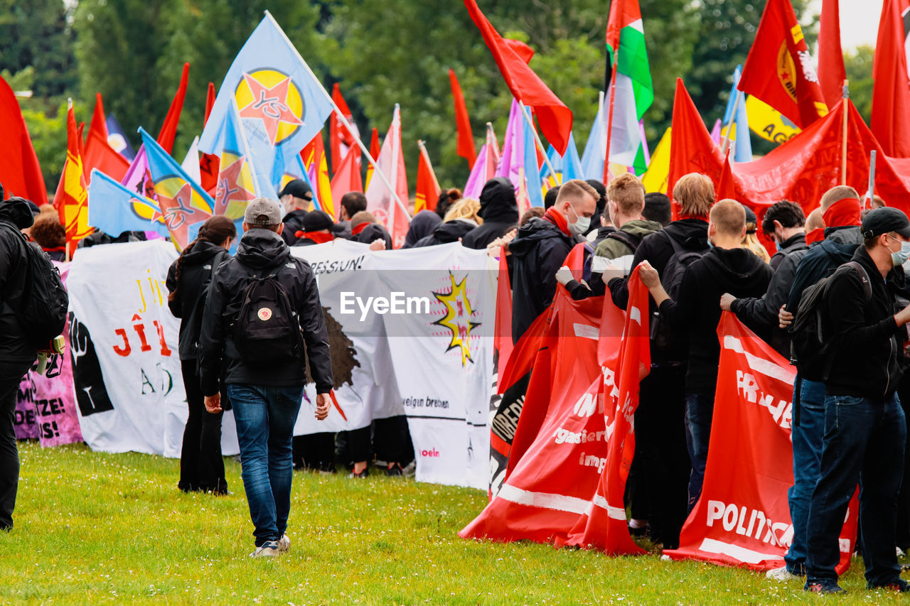 REAR VIEW OF PEOPLE WALKING IN TRADITIONAL FLAGS