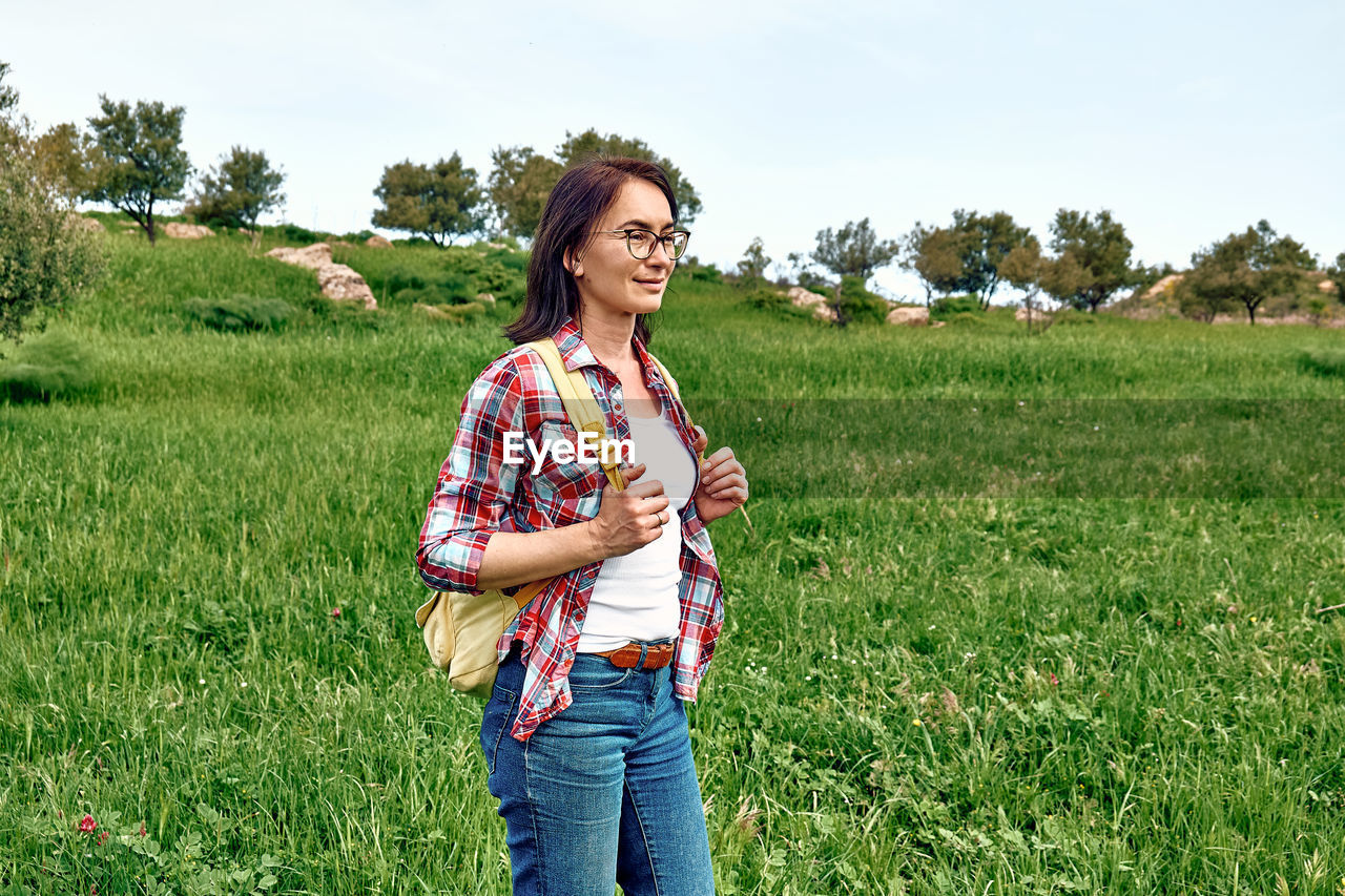 Happy beautiful carefree woman walking on a spring meadow with green grass. hiking outdoors