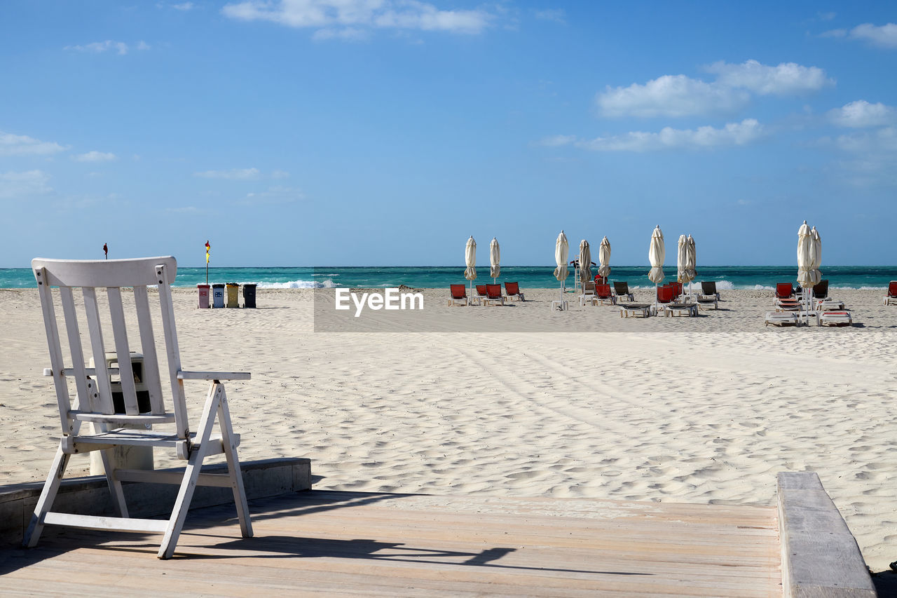 An empty beach near abu dhabi with turquoise water and umbrellas