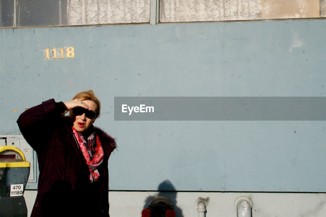 Woman shielding eyes while standing by wall