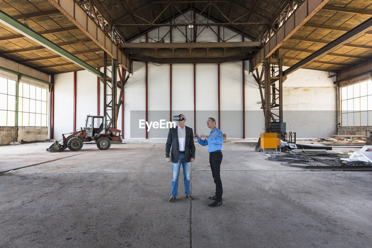 Two businessmen with vr glasses talking in old industrial hall