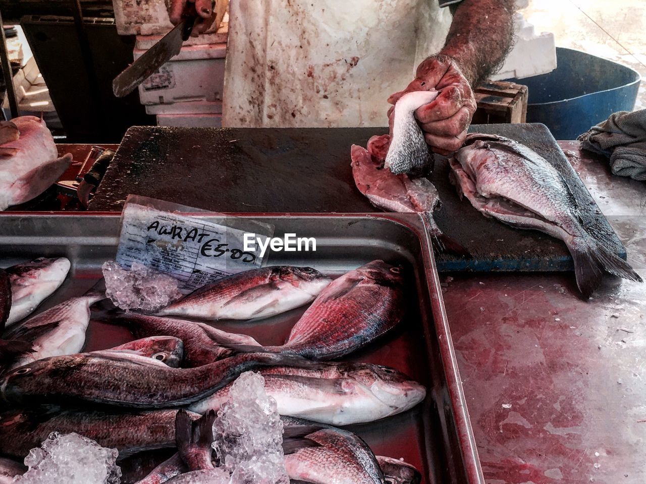 Midsection of butcher cutting fish at market