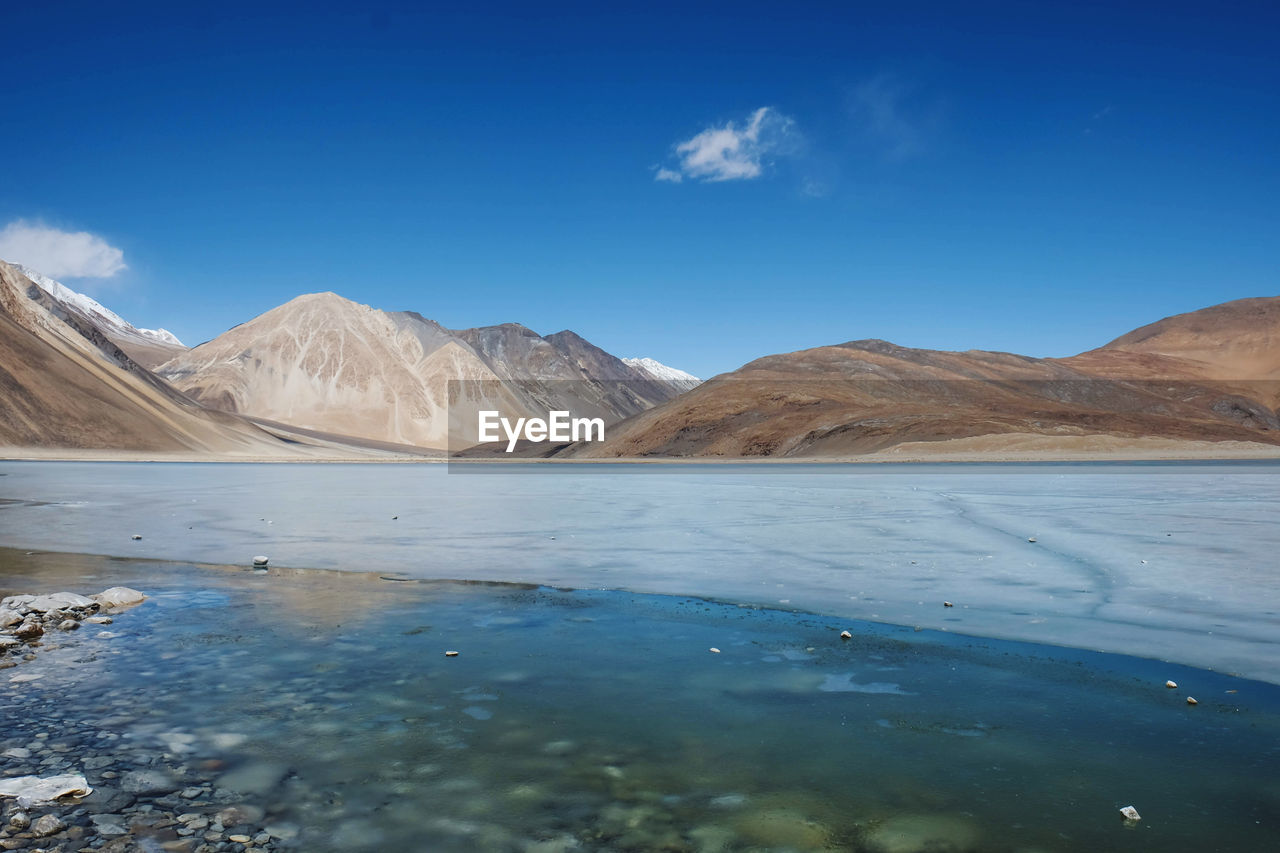 Scenic view of lake and mountains against blue sky